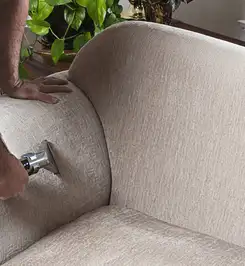 Professional upholstery cleaner deep-cleaning a fabric sofa with a handheld extraction tool and hose Arvada, CO.